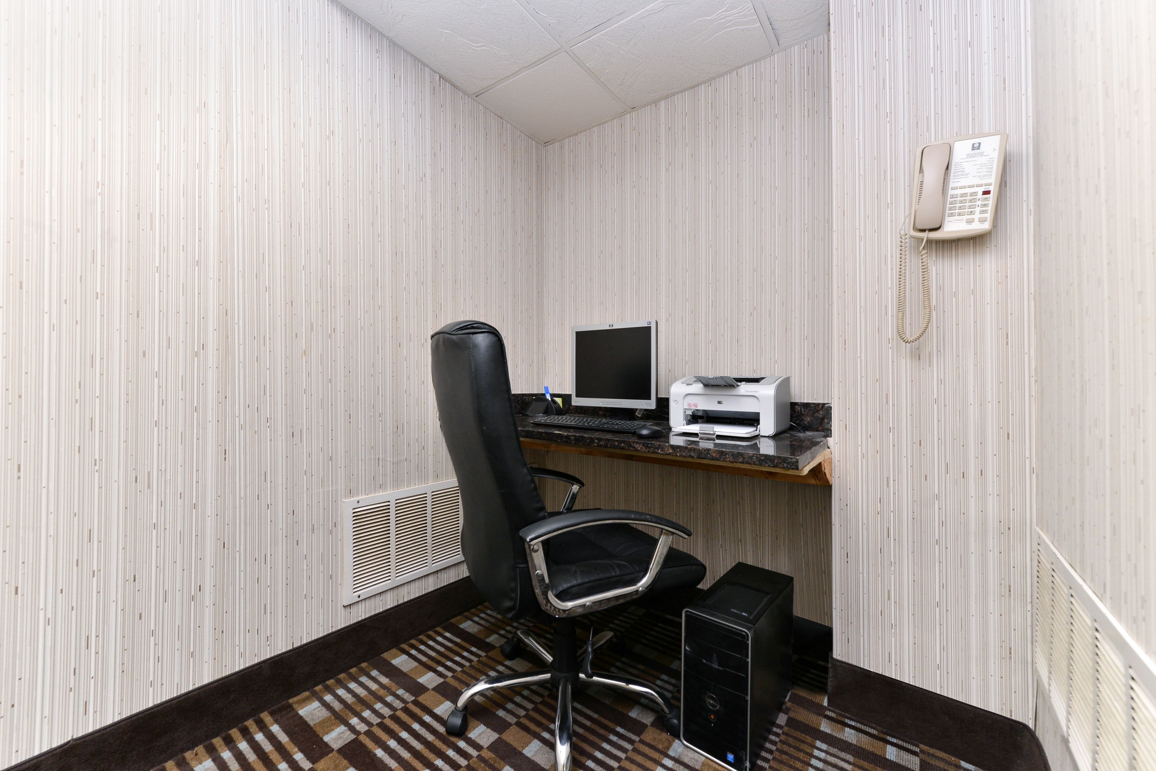 A small office with a desk, computer, printer, and telephone.