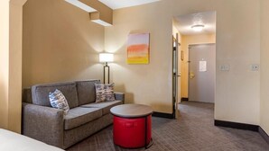Ein Hotelzimmer mit einer Couch, einer roten Mülltonne, einer Lampe und einem Bild an der Wand.