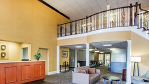 Eine Hotelhalle mit einer Rezeption, einer Couch, einem Couchtisch und einer Treppe.