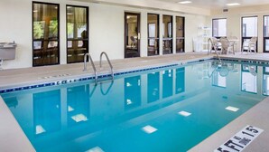 Ein Hallenbad mit klarem Wasser, umgeben von Fenstern und Liegestühlen.
