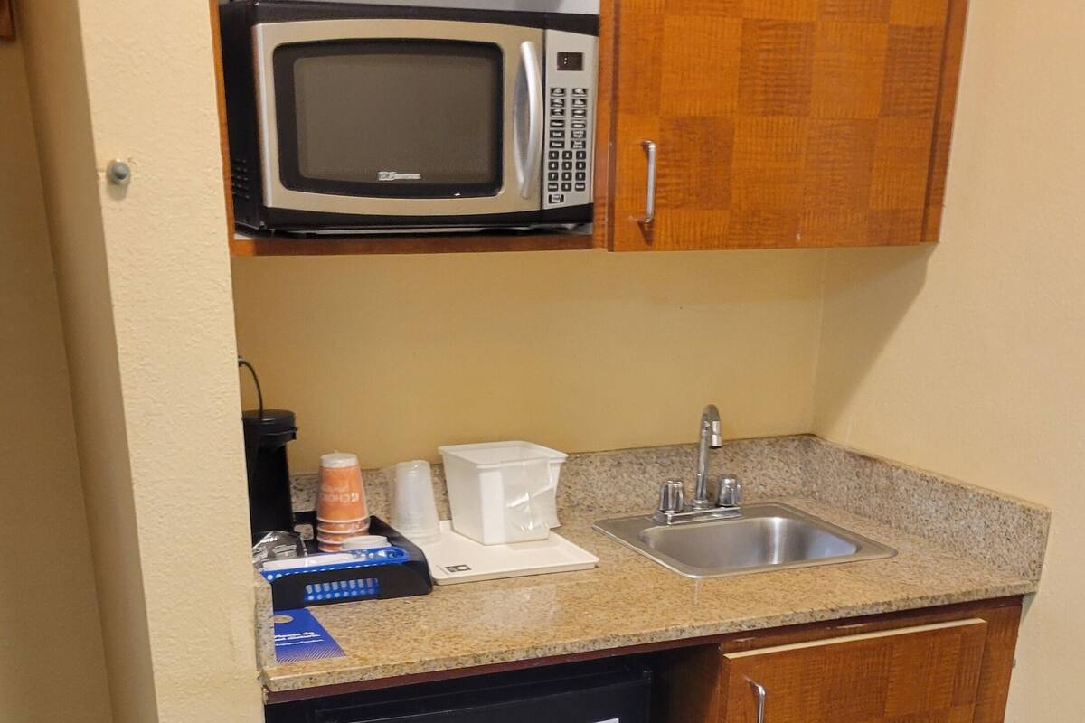 A compact kitchen with a microwave, sink, and refrigerator.
