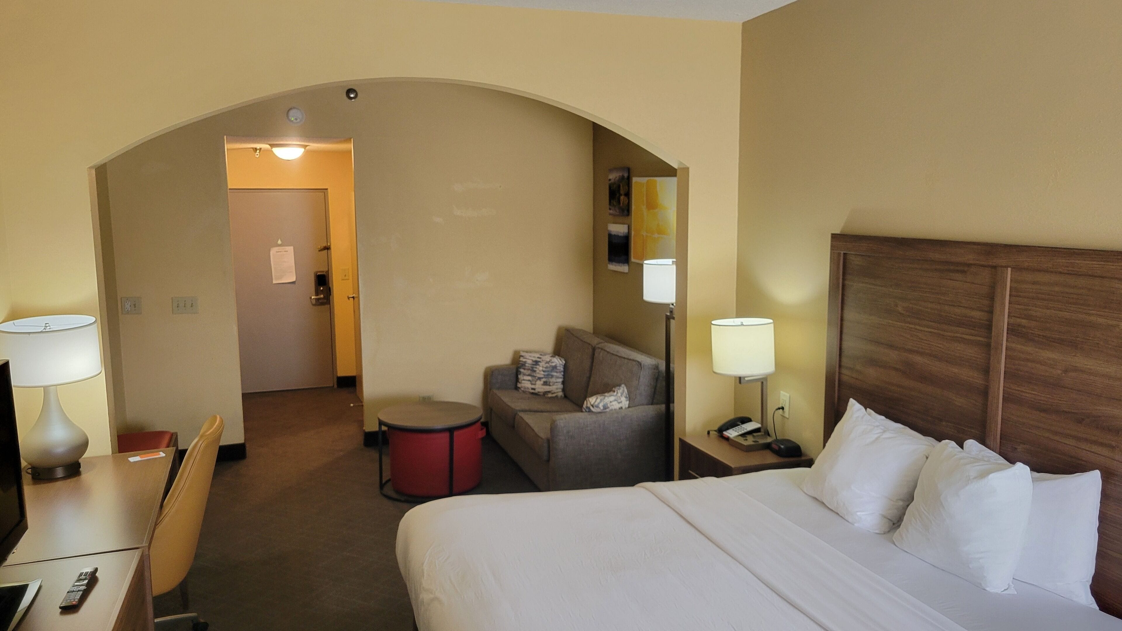Een hotelkamer met een bed, een bureau met lamp, een bank, een kleine tafel en een stoel.