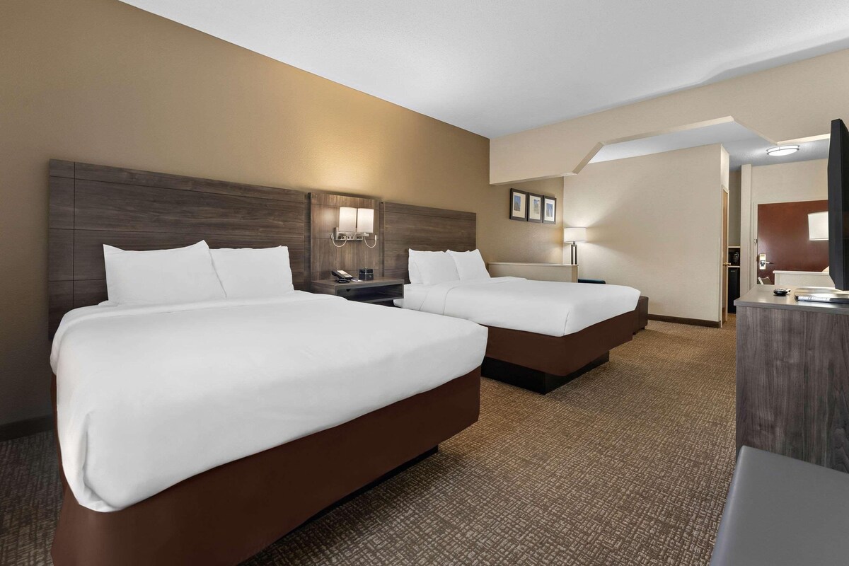 A hotel room with two beds, a desk, and a television.