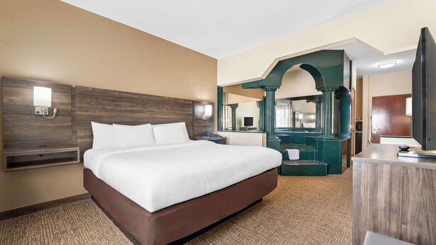 A hotel room with a large bed, a desk, a mirror, and a television. - Comfort Suites near Robins Air Force Base (Warner Robins)