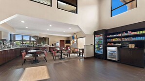 A modern kitchen with a dining area, large windows, and a beverage refrigerator. - Comfort Suites near Robins Air Force Base (Warner Robins)
