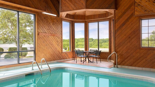 A swimming pool with wooden walls and large windows offering views of greenery. - Baymont by Wyndham Winchester (Winchester)