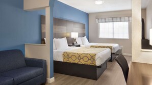 A hotel room with two beds, a sofa, a desk, and a window with blinds. - Baymont by Wyndham Winchester (Winchester)