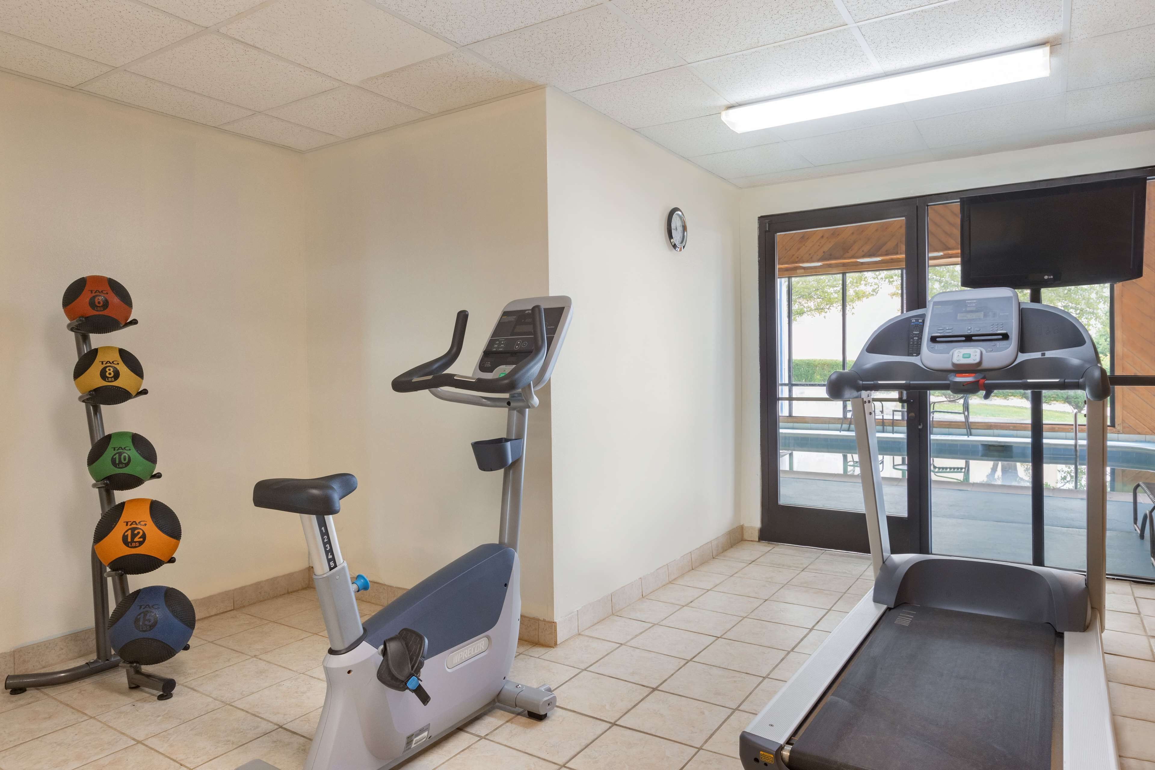 Un gimnasio con cinta de correr, bicicletas estáticas y equipo de levantamiento de pesas.