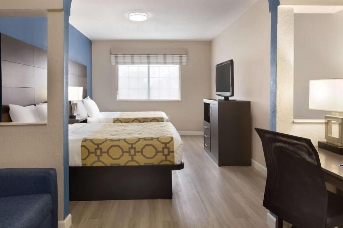 Une chambre d’hôtel avec un lit, un bureau, une chaise, une télévision et une fenêtre.