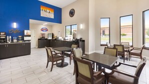 A hotel dining area with a coffee station, a clock, and large windows offering a view of the outside. - Baymont by Wyndham Winchester (Winchester)