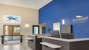 A Baymont Inn & Suites reception area with a blue accent wall, a large window with a view of a pool, and a modern reception desk. - Baymont by Wyndham Winchester (Winchester)