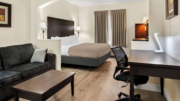 Ein Hotelzimmer mit einem Bett, einem Schreibtisch, einem Sessel, einer Couch und einem Fernseher.
