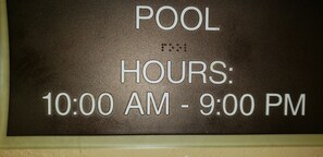 A sign indicating pool hours from 10:00 AM to 9:00 PM.