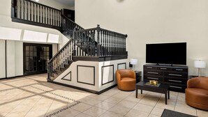 Ein geräumiger Wohnbereich mit Treppe, einem Flachbildfernseher, Ledersesseln und einer schwarzen Unterhaltungsanlage.