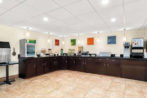 A kitchen area with a refrigerator, coffee machine, and various kitchen appliances.