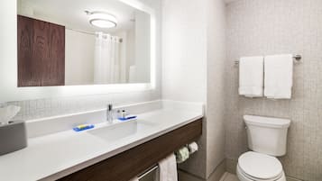 A bathroom with a white sink, a mirror, a toilet, and a towel rack.