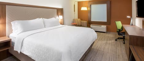Una habitación de hotel con una cama grande, un escritorio con silla, un televisor y una ventana.