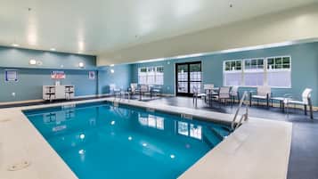 A swimming pool with lounge chairs and a safety sign.
