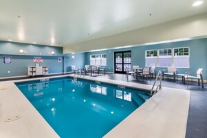 A swimming pool with lounge chairs and a safety sign.