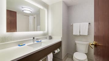 Une salle de bain moderne avec un grand miroir, deux lavabos, des toilettes et un espace douche.
