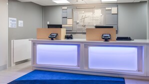 A hotel reception desk with two counters, a blue carpet, and a sign indicating complimentary breakfast.