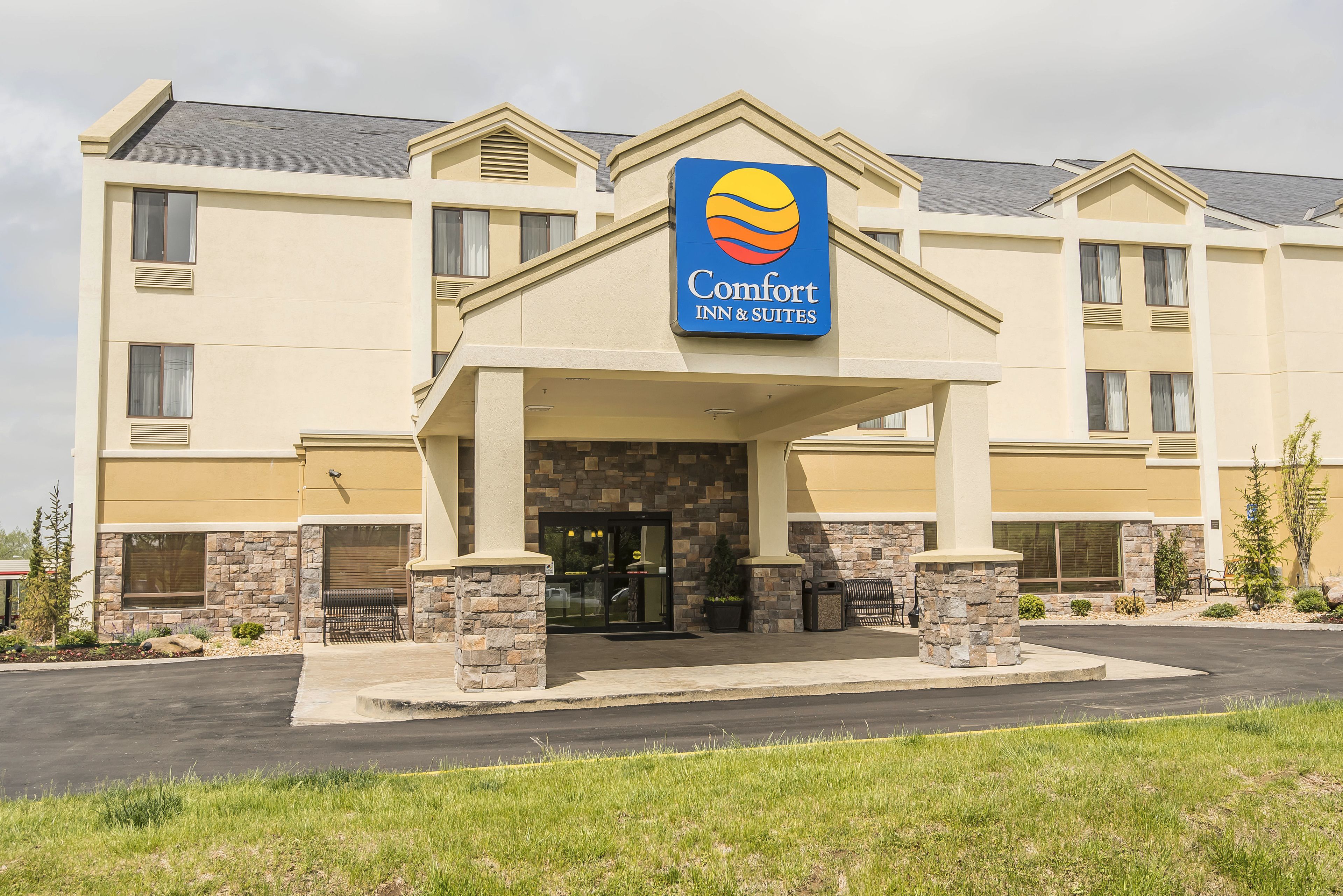 Un hotel Comfort Inn & Suites con fachada de piedra, amplio acceso y cielo despejado.
