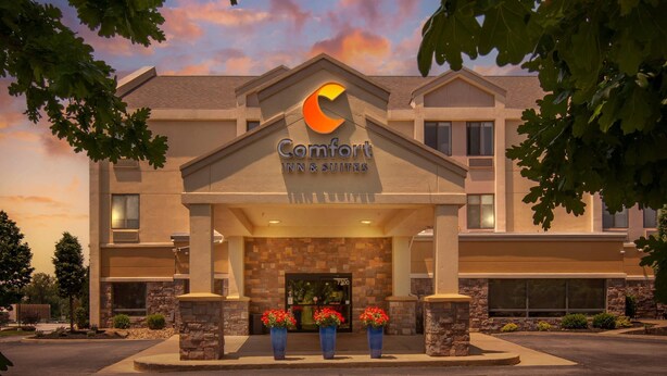 A Comfort Inn & Suites building with a prominent logo, a stone facade, and three potted plants in front. - Comfort Inn & Suites Kansas City - Northeast (Kansas City)