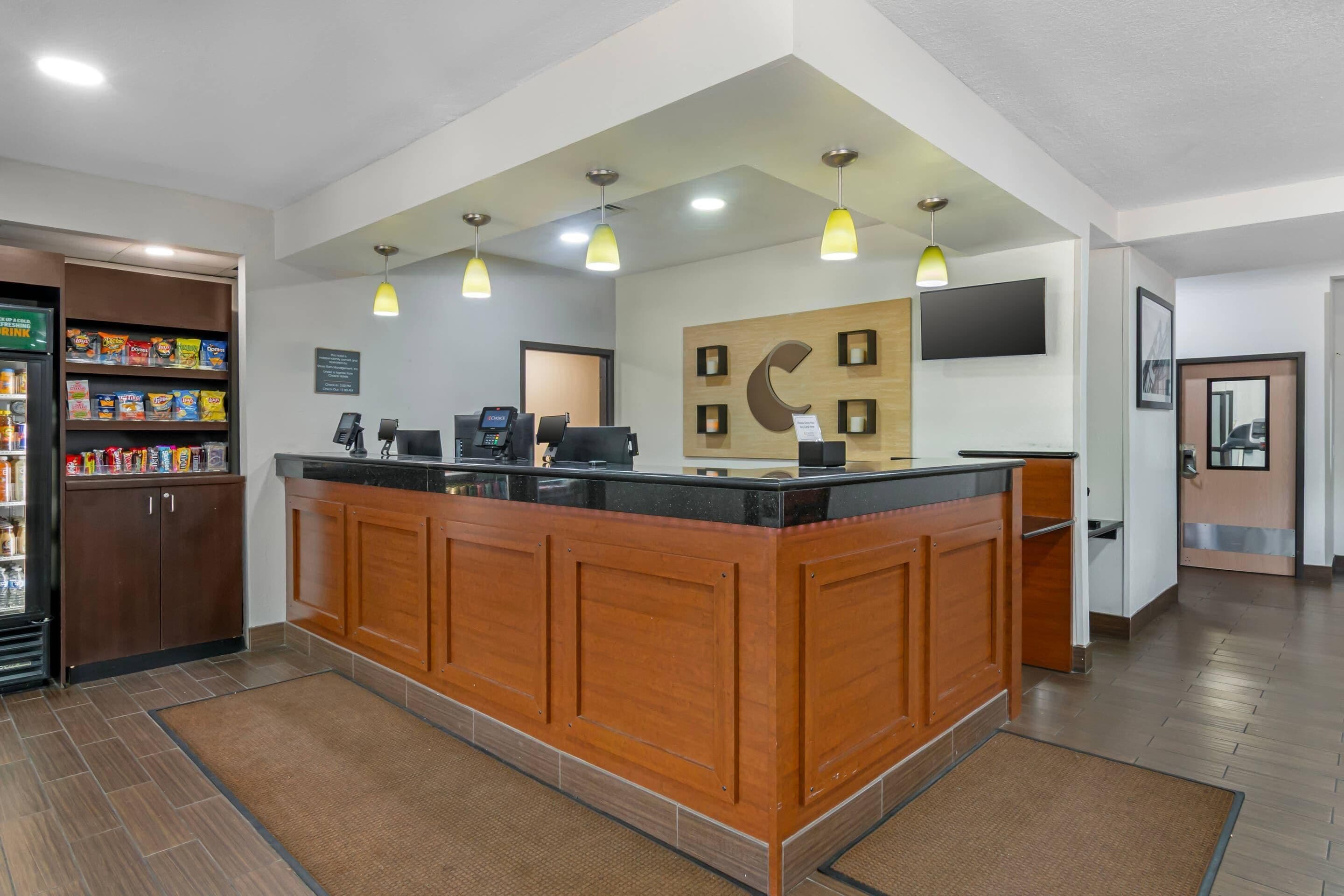 A reception area with a wooden counter, a refrigerator stocked with snacks, a cash register, and a flat-screen TV mounted on the wall.