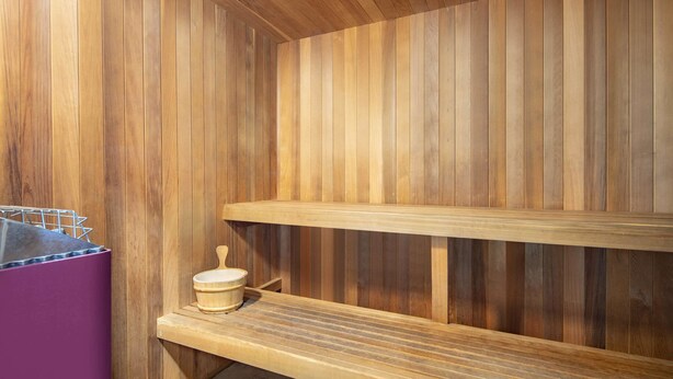 Una sauna de madera con bancos y una pequeña mesa de madera.