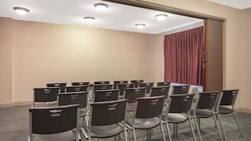 Ein Konferenzraum mit Reihen von Stühlen, einem Teppichboden und einer Tür mit Vorhang.
