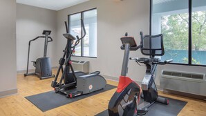 Un gimnasio con bicicletas estáticas, una cinta de correr y una máquina de remo.