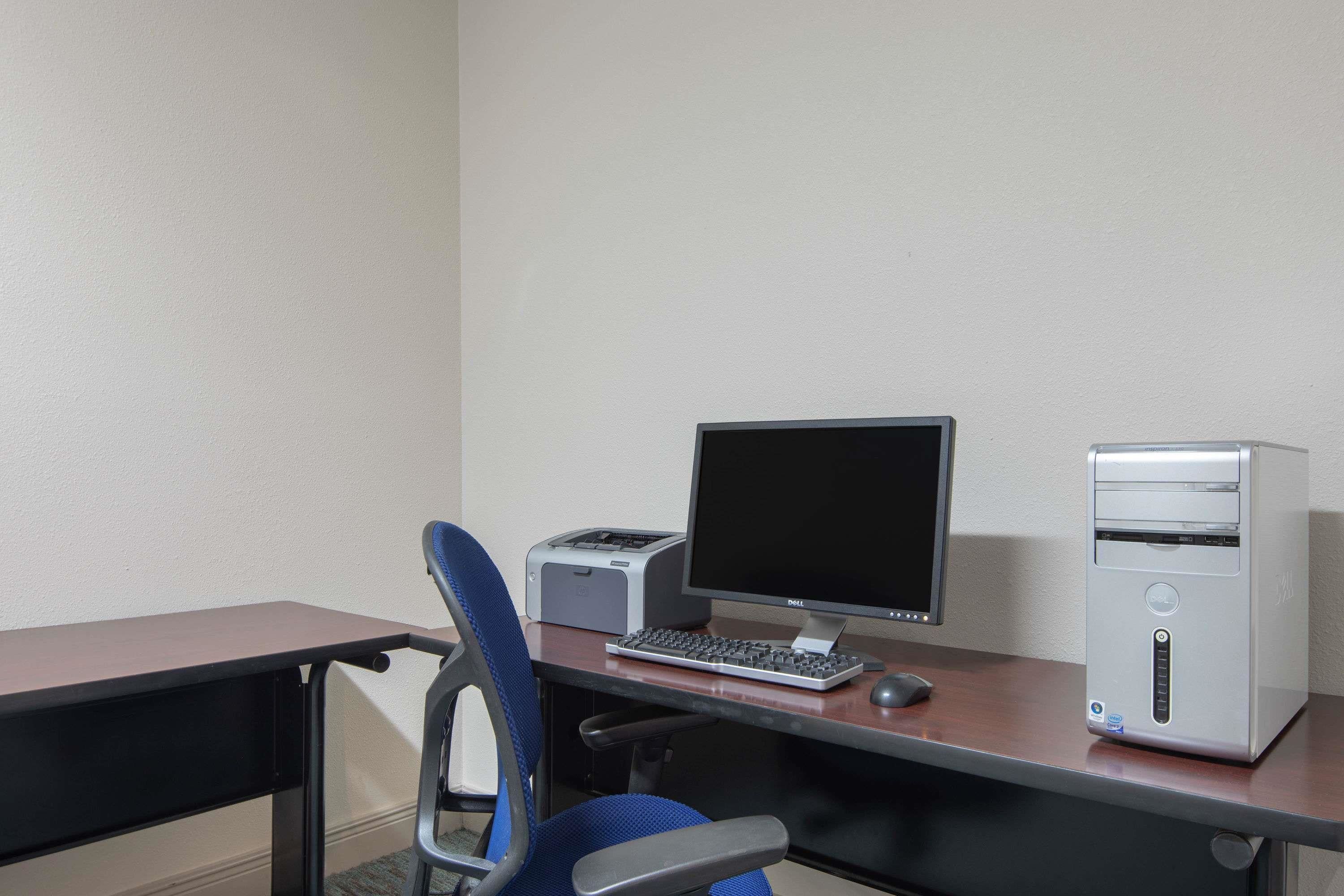 A desk with a computer, keyboard, and monitor. There is a chair and a printer on the desk.