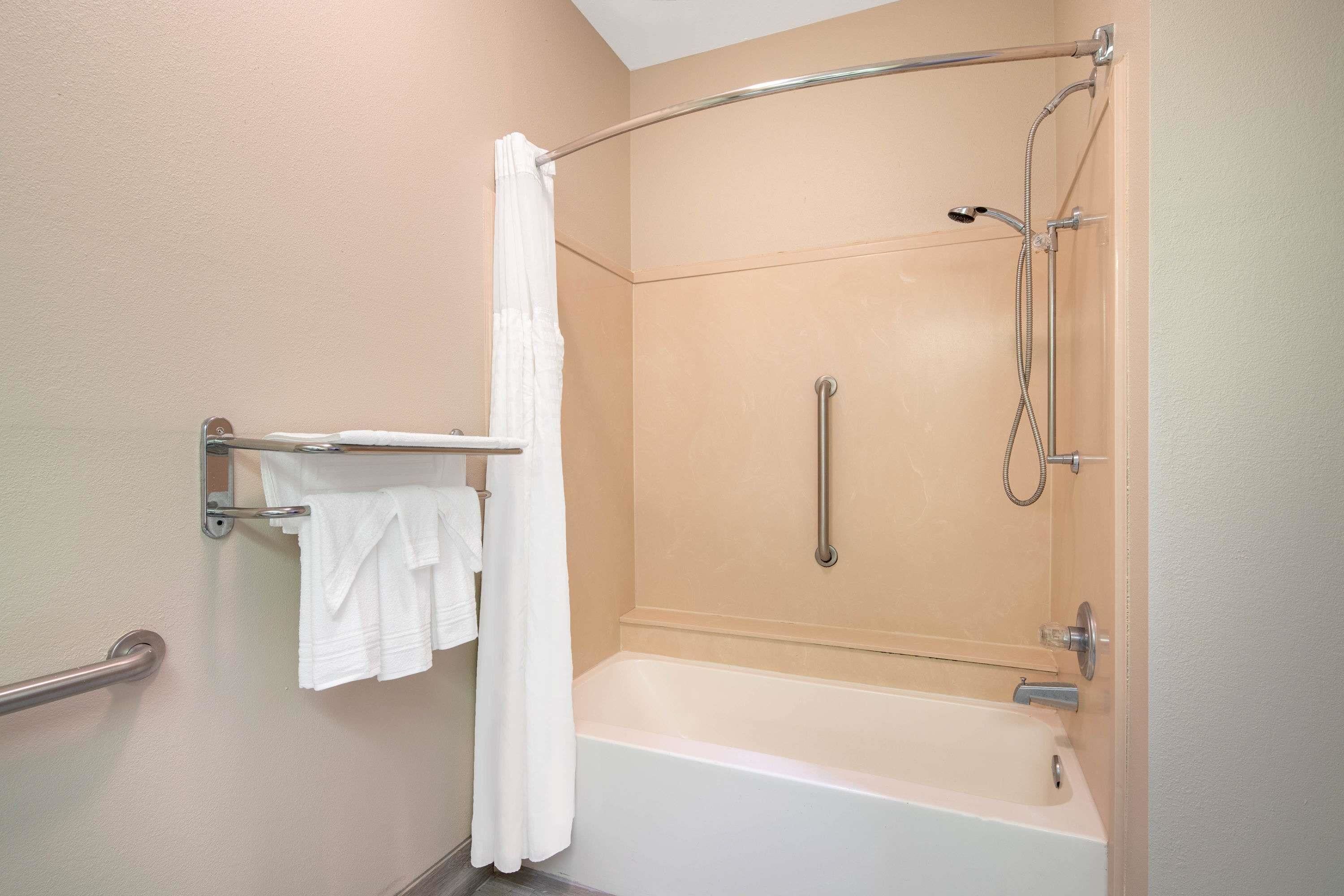 A modern bathroom with a walk-in shower, a grab bar, and a towel rack.