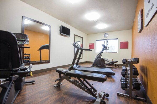 Un gimnasio con cintas de correr, una prensa de pesas y mancuernas.