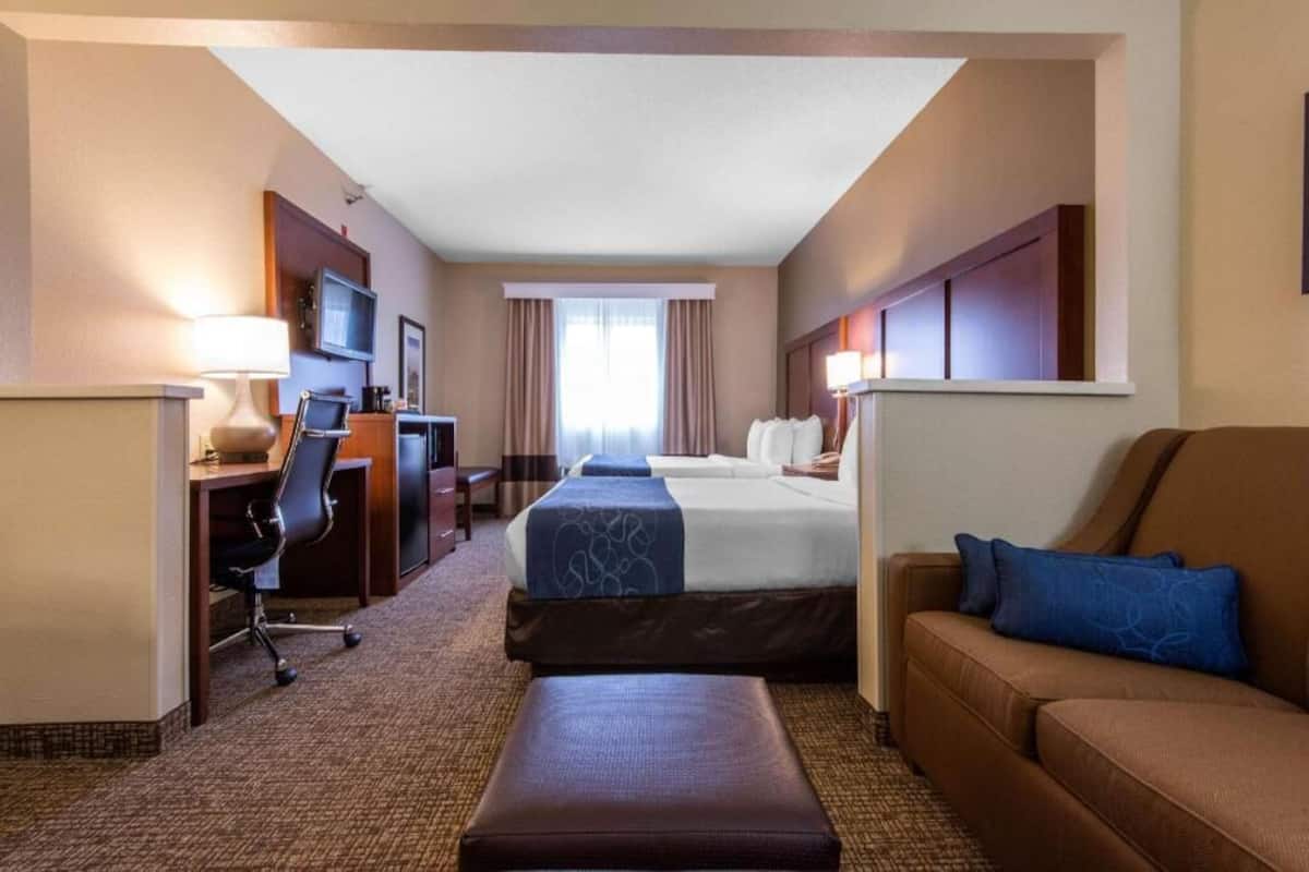 A hotel room with a bed, a desk, a chair, a sofa, and a television.