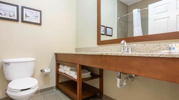Un baño con inodoro, lavamanos con espejo y cuadros en la pared.
