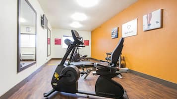 Een sportschool met cardioapparaten, spiegels en motiverende posters op de muren.