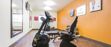 A gym with cardio machines, mirrors, and motivational posters on the walls.