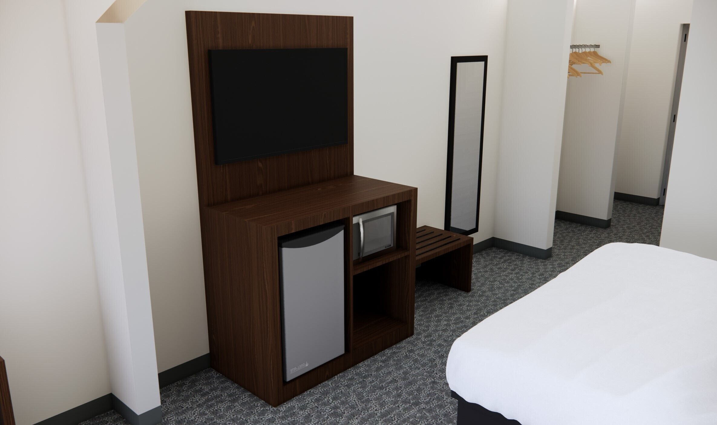 A hotel room with a bed, a TV mounted on a wooden cabinet, a microwave, and a mirror.