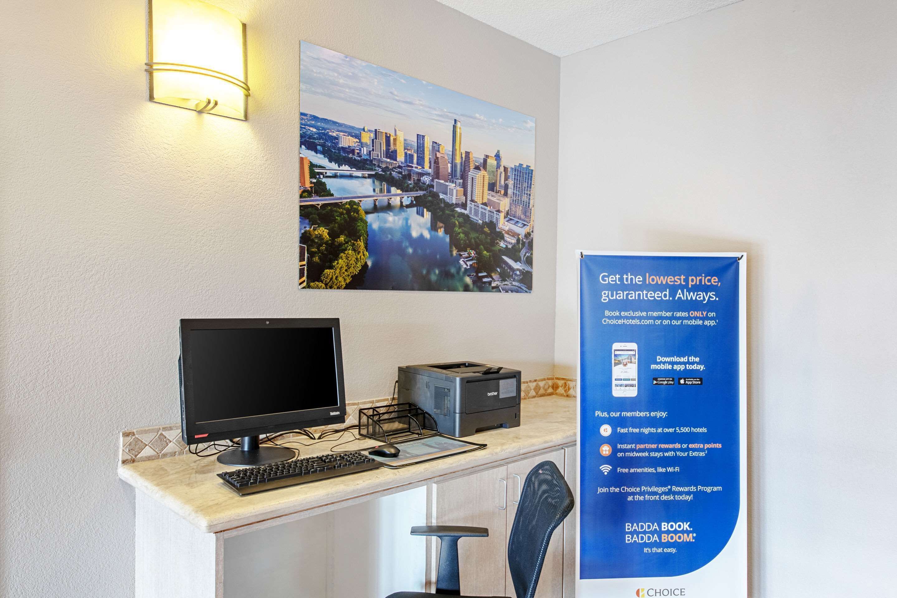 Un mostrador de recepción de hotel con una computadora, una impresora y un cartel que anuncia tarifas de membresía.