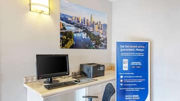 Un mostrador de recepción de hotel con una computadora, una impresora y un cartel que anuncia tarifas de membresía.