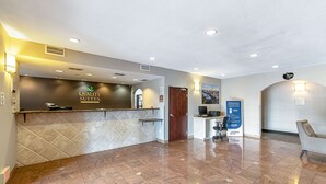 A hotel reception area with a reception desk, a computer, and a seating area. - Quality Suites Austin South St. Elmo District (Austin)