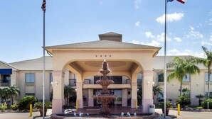 Ein Hotel mit Eingangsbereich, einem Brunnen, überdachter Wartezone und Flaggen.
