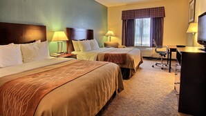Ein Hotelzimmer mit zwei Betten, einem Schreibtisch, einem Stuhl, einem Fernseher und einem Fenster mit Vorhängen.