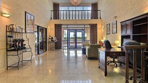 Eine ger äumige Lobby mit hochglänzendem Boden, einer Kaffeestation, einer Sitzecke und einer Treppe in die oberen Etagen.