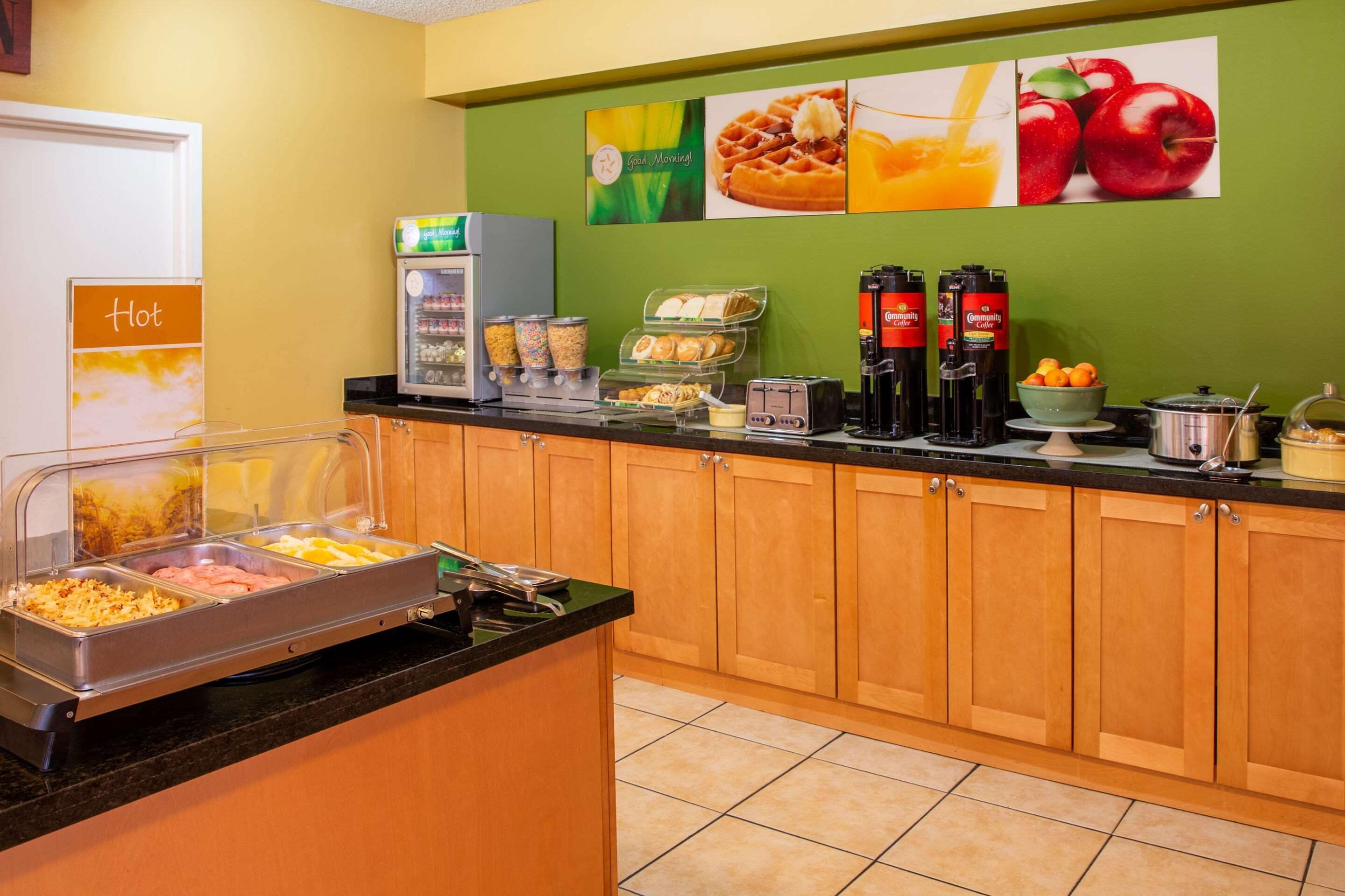 A breakfast bar with various food options, a coffee station, and a refrigerator.