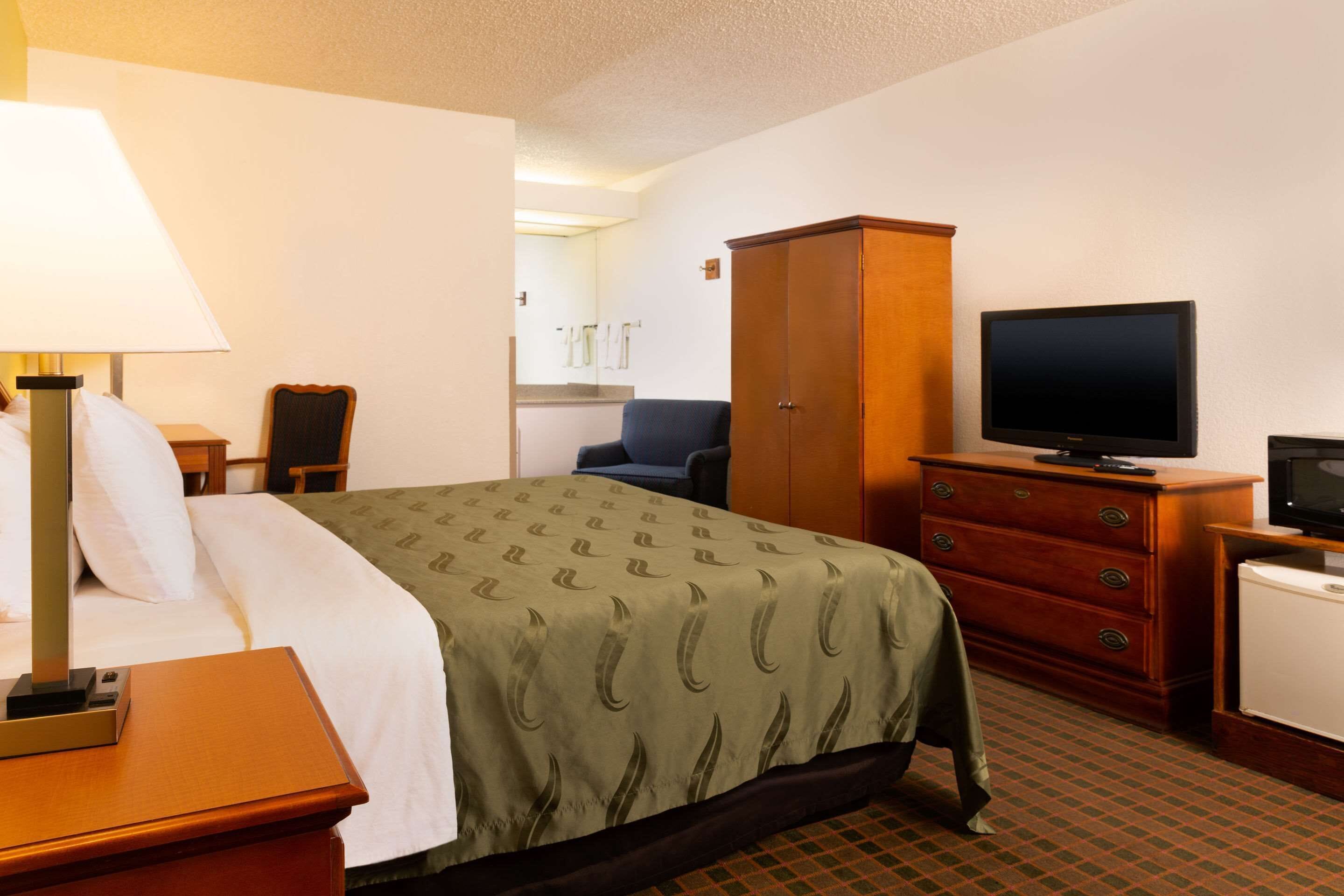 Ein Hotelzimmer mit einem Bett, einem Fernseher, einem Schminktisch, einem Schreibtisch und einem Sessel.