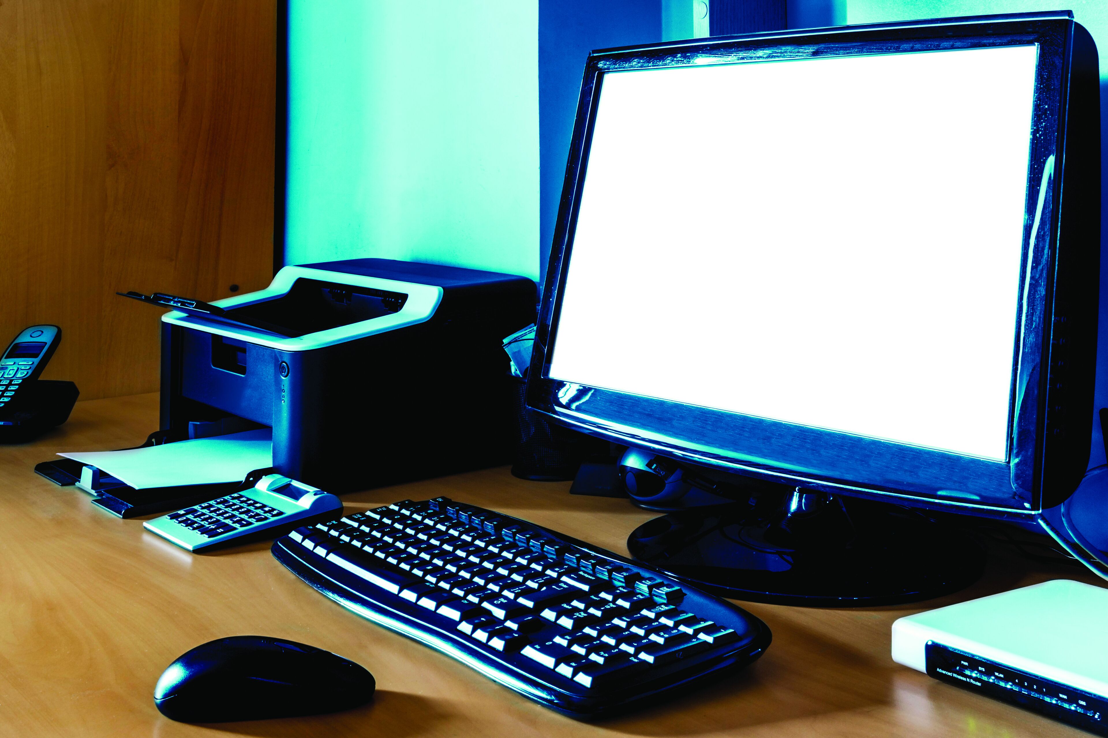 A desk with a computer, keyboard, mouse, and a calculator.