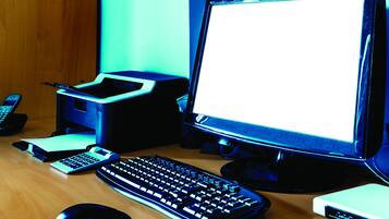 A desk with a computer, keyboard, mouse, and a calculator.