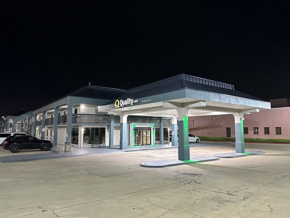 A hotel with a covered parking area, a sign for 'Quality Inn by Chase Hotels', and a car parked in front.